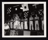USO entertainment. Woman singing in front of group of men in &quot;sailor&quot; costumes 